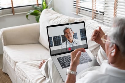 Patient on couch having telemedicine visit with doctor on laptop