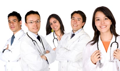 friendly young doctors smiling over a white background - focus is on the female doctor on the right